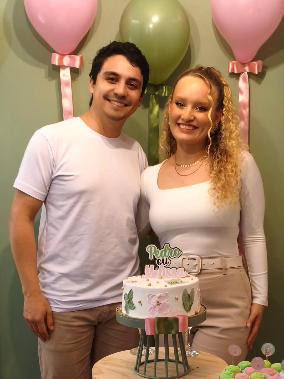 Duas pessoas em uma comemoração com bolo temático e decoração em tons de rosa e verde
